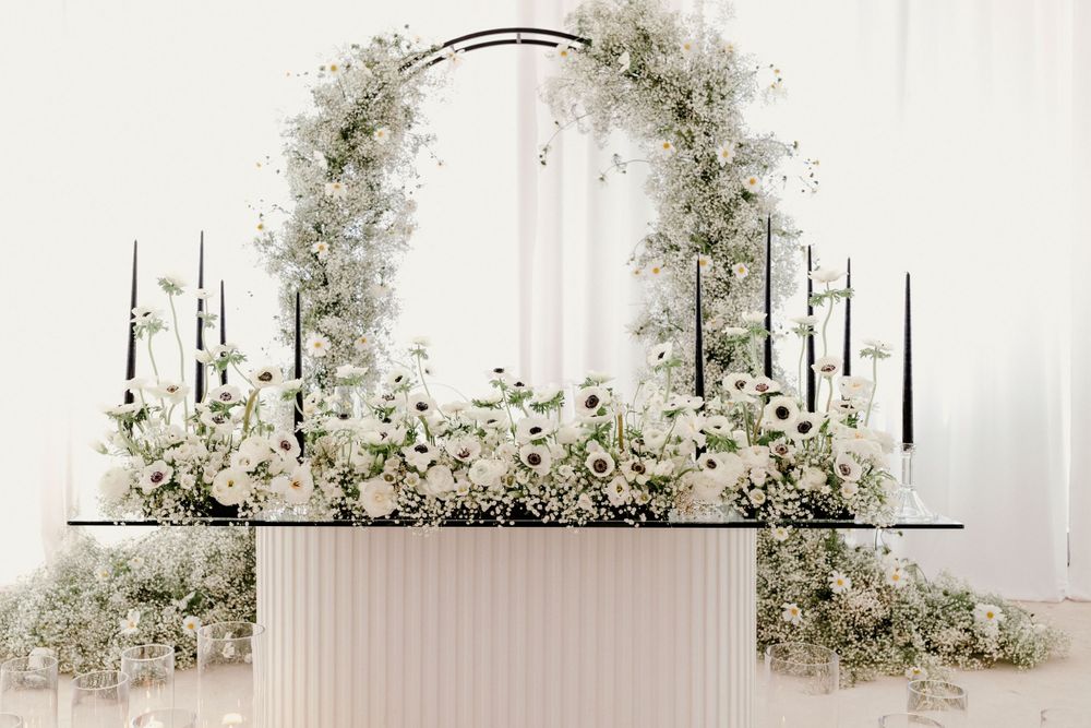 White floral arch with candelabras and baby's breath arrangements framing an elegant wedding altar.