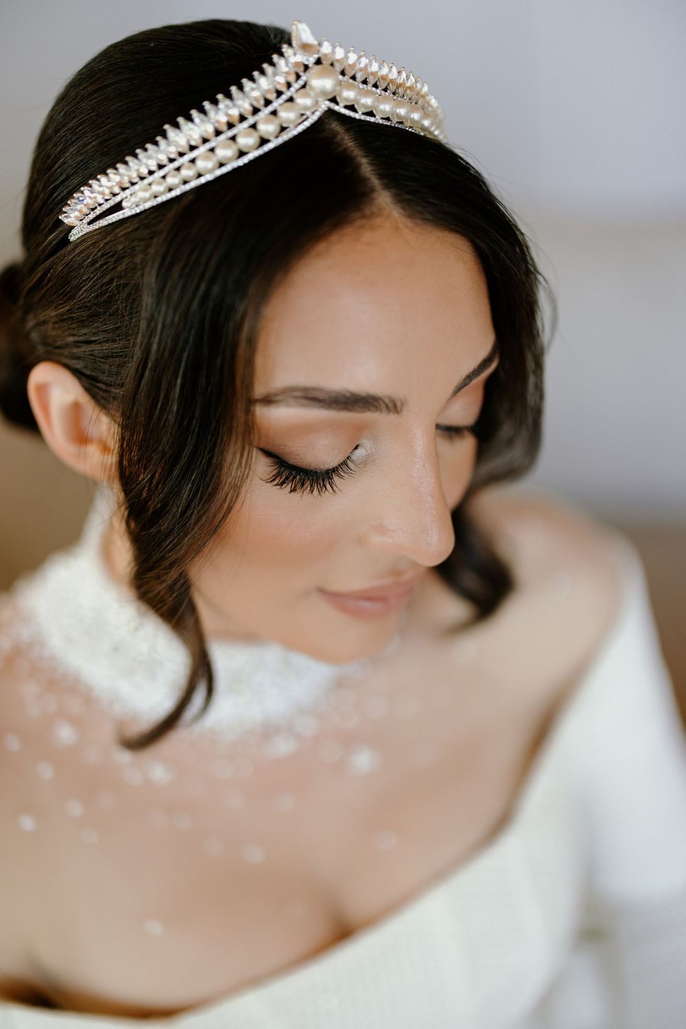 Close up beauty shot showing detailed crystal tiara and natural bridal makeup.