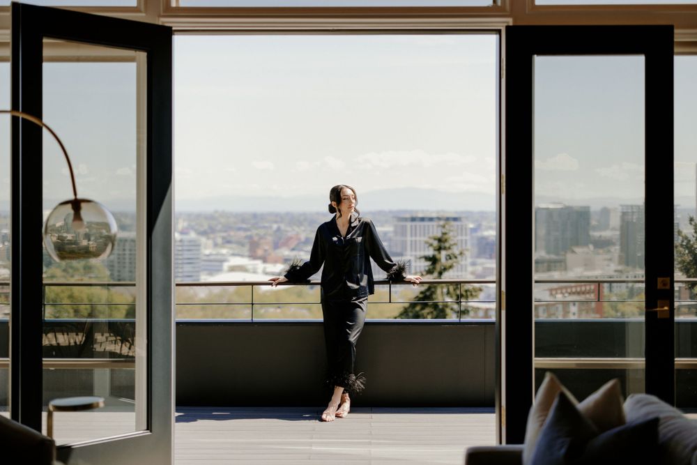 Silhouette of person standing on balcony overlooking cityscape in modern apartment.