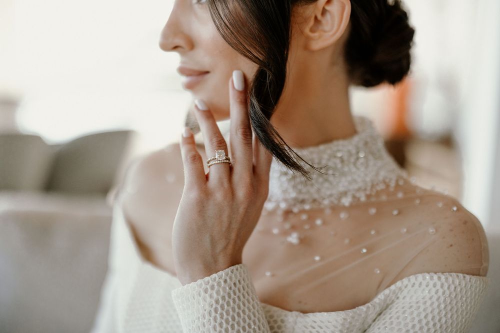 Side profile of bride wearing elegant beaded neckline and white textured gown.