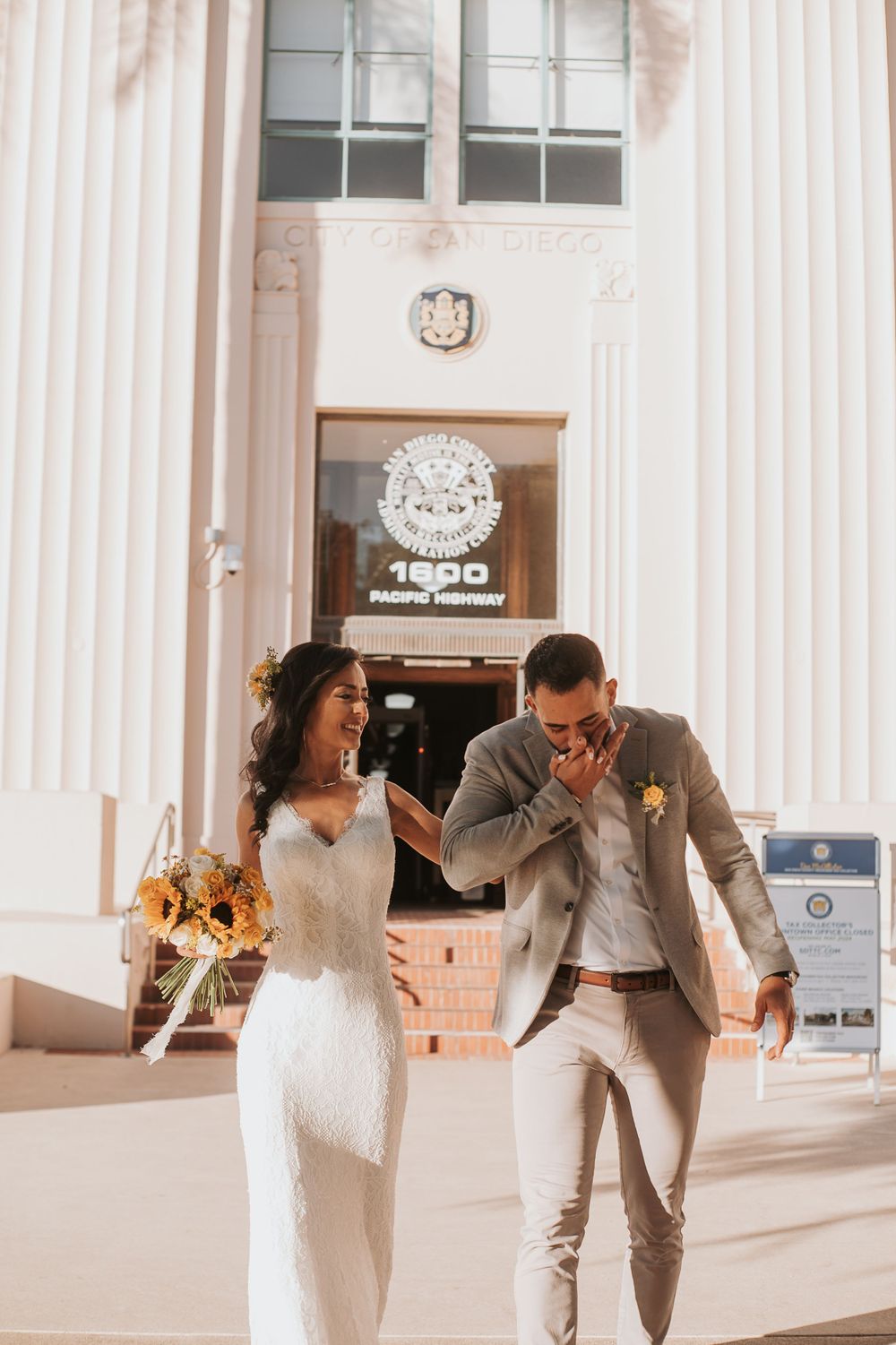 Joyful couple dancing and celebrating outside a columned building entrance.