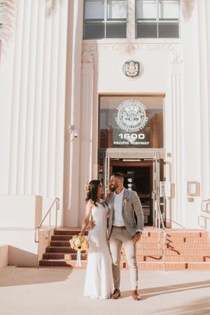 Wedding couple walks together along a classic building exterior with white columns.