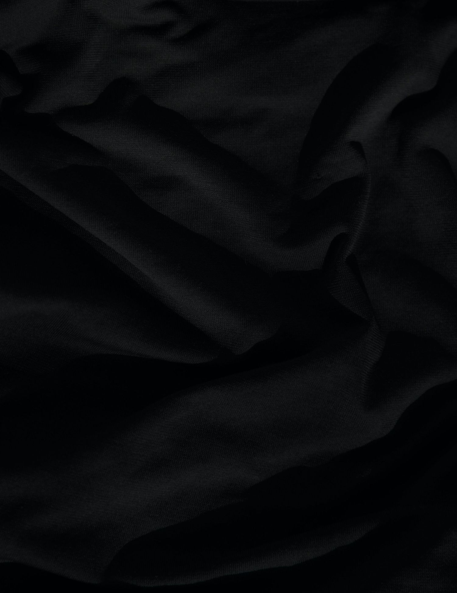 Close-up texture of wrinkled black fabric with deep shadows and folds.