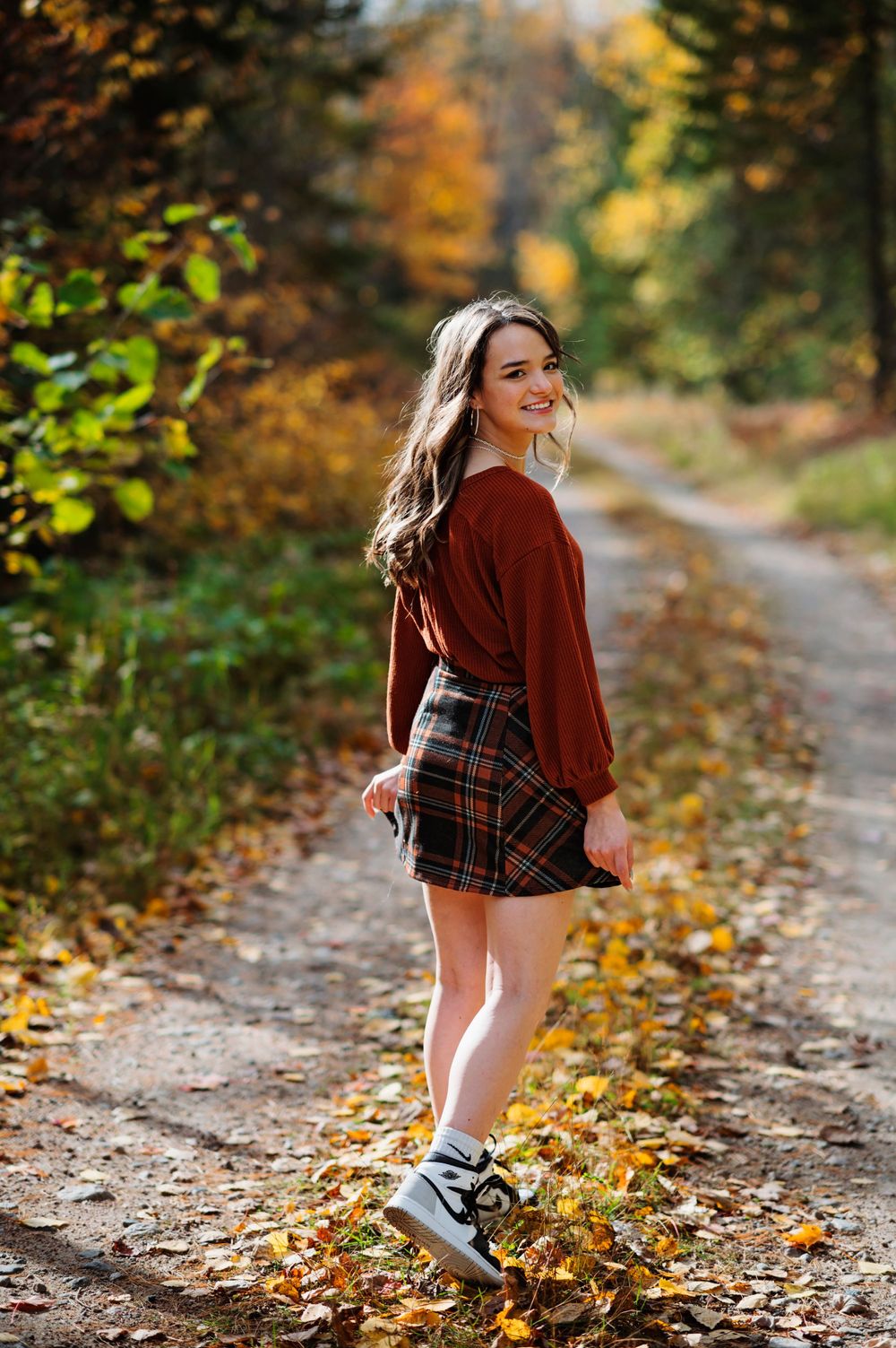 Angeline walking through fall leaves for senior pictures.