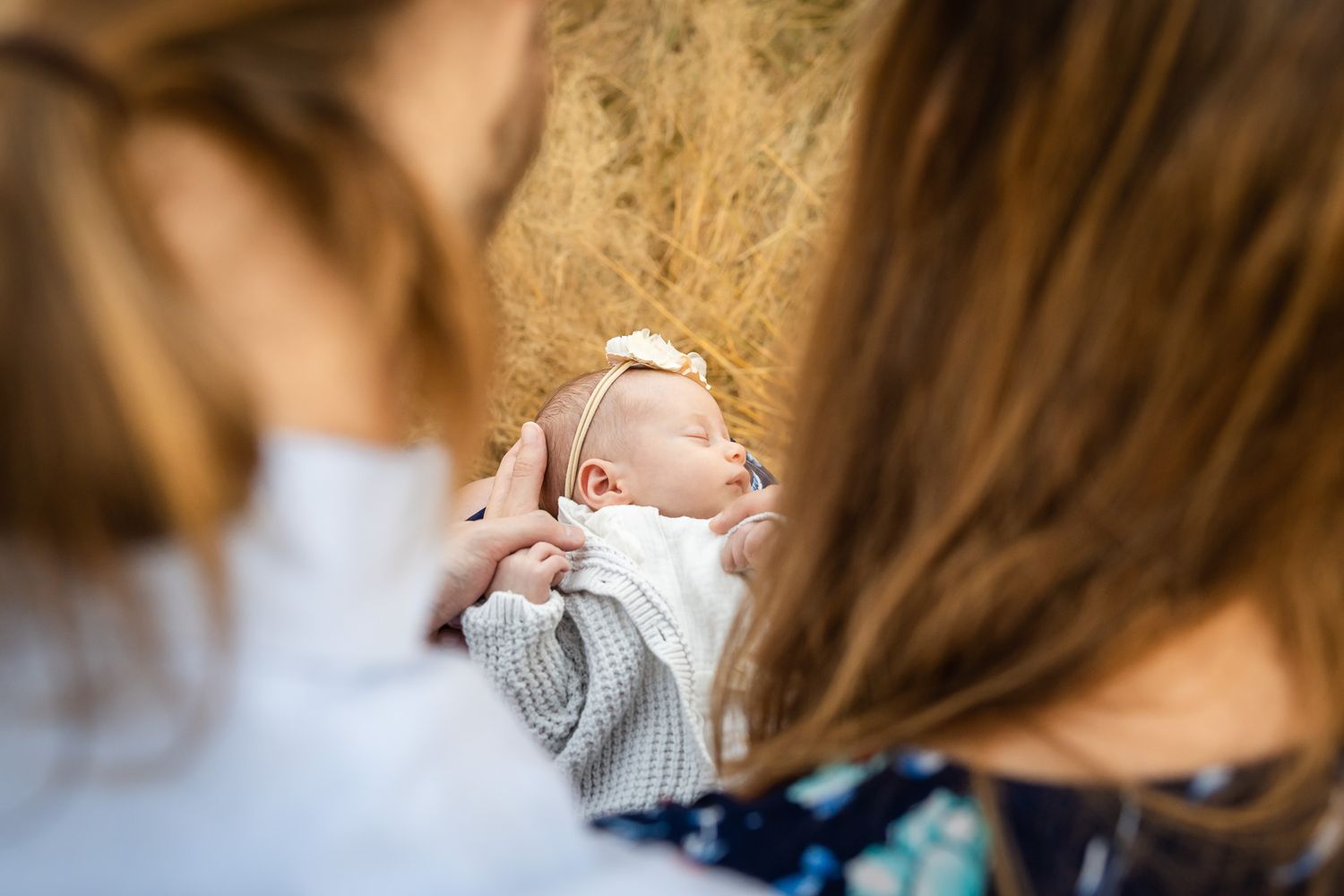 Peek a boo photo of newborn baby sleeping while parents look on, in Woodinville