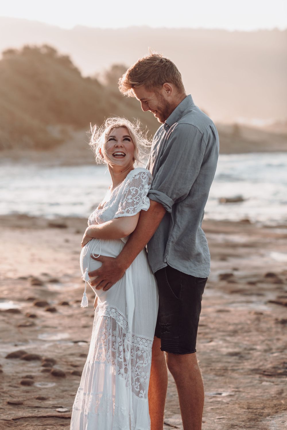 Romantic sunset beach portrait with coastal cliffs in the background.