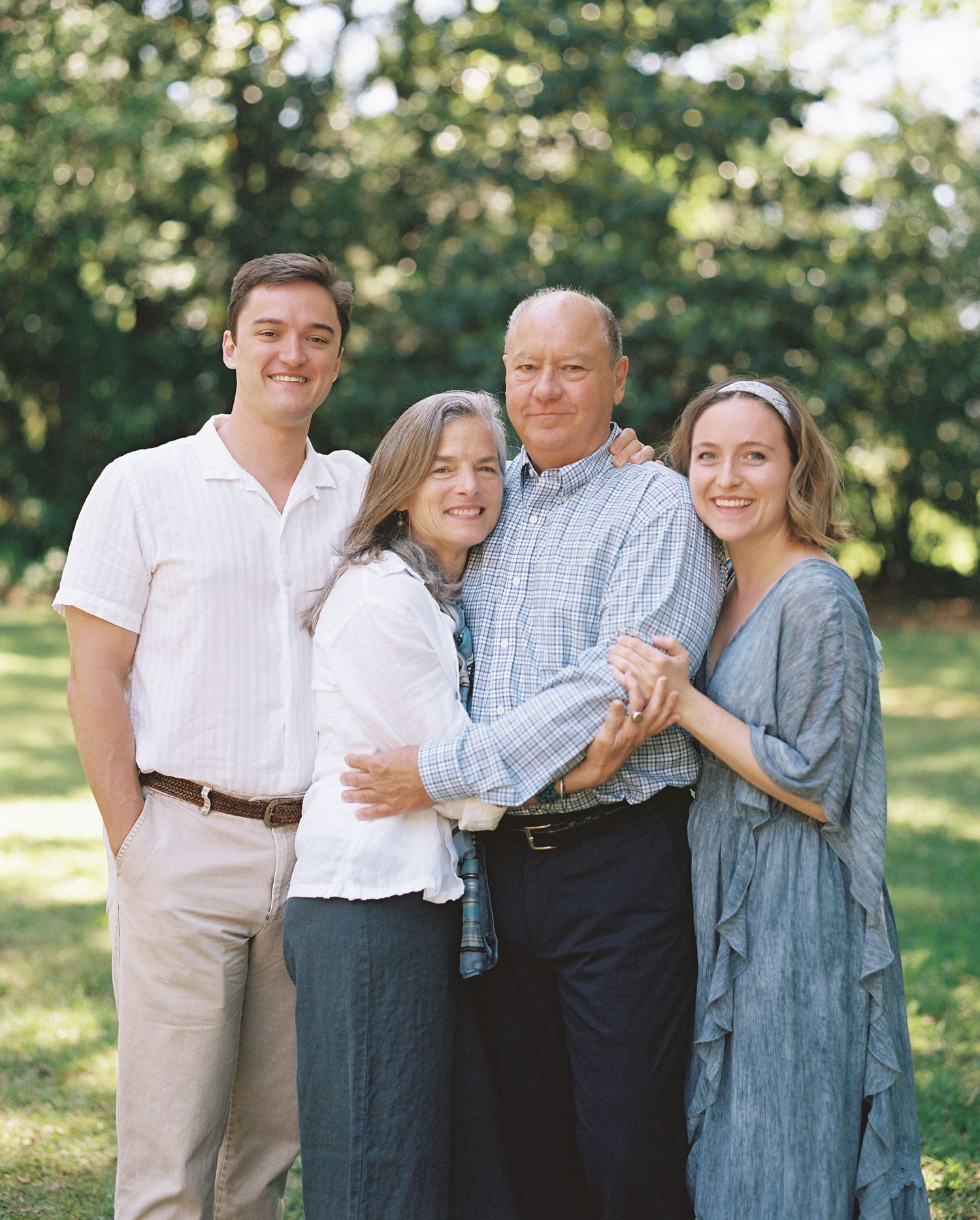 Family of four posing together outdoors in coordinated casual attire.