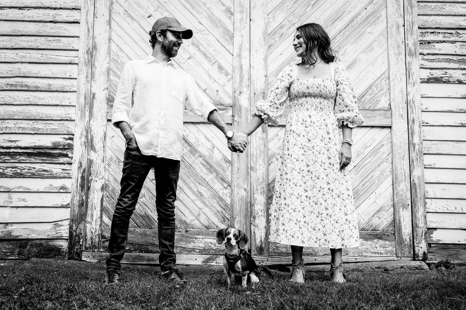 black and white image of young couple holding hands over beagle dog