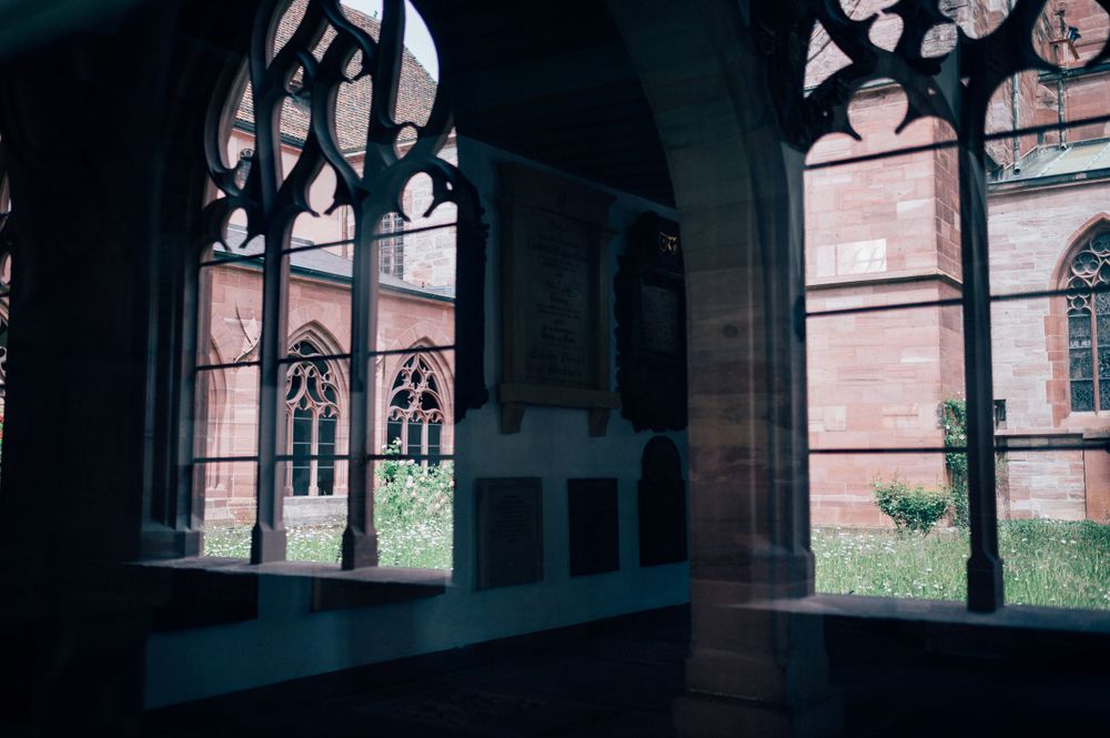 Gothic architecture with arched windows and cloisters in dramatic lighting.
