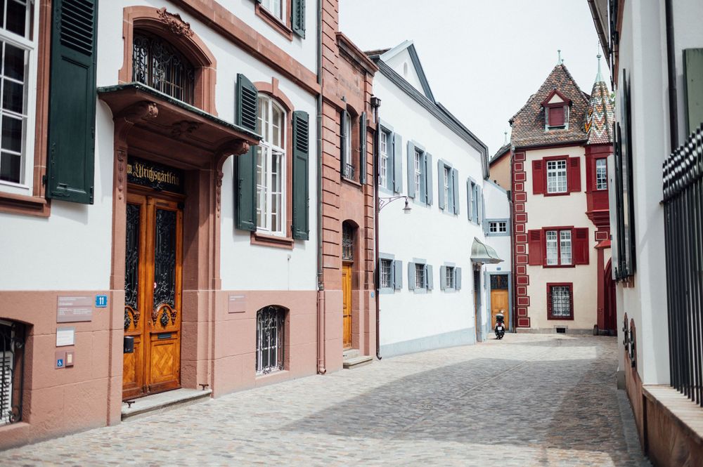 Charming narrow cobblestone street with colorful historic buildings and shuttered windows.