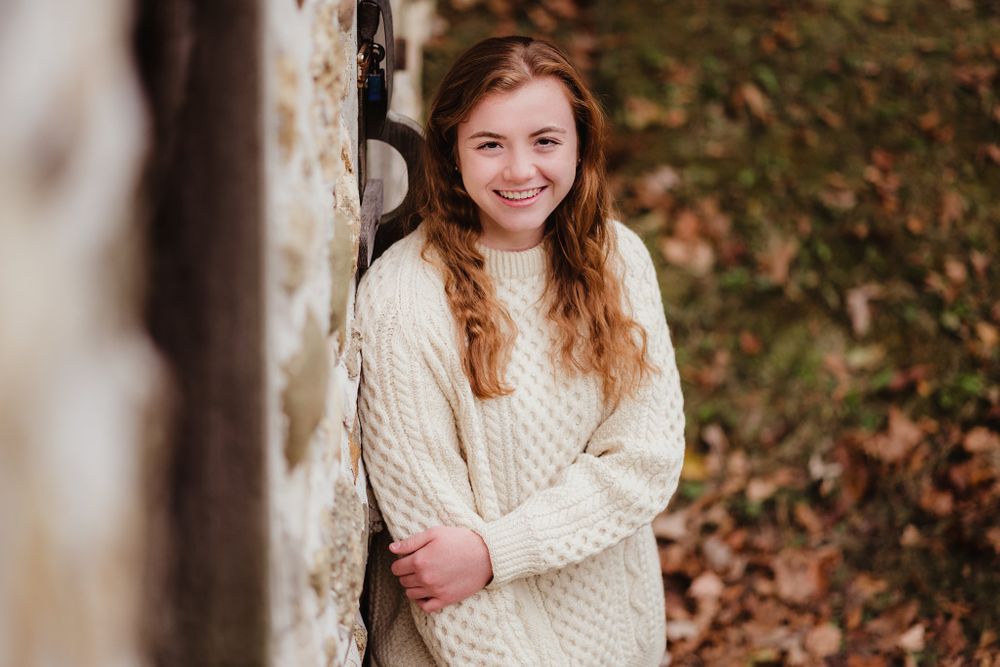 Casual autumn portrait against a weathered wall in warm natural light.