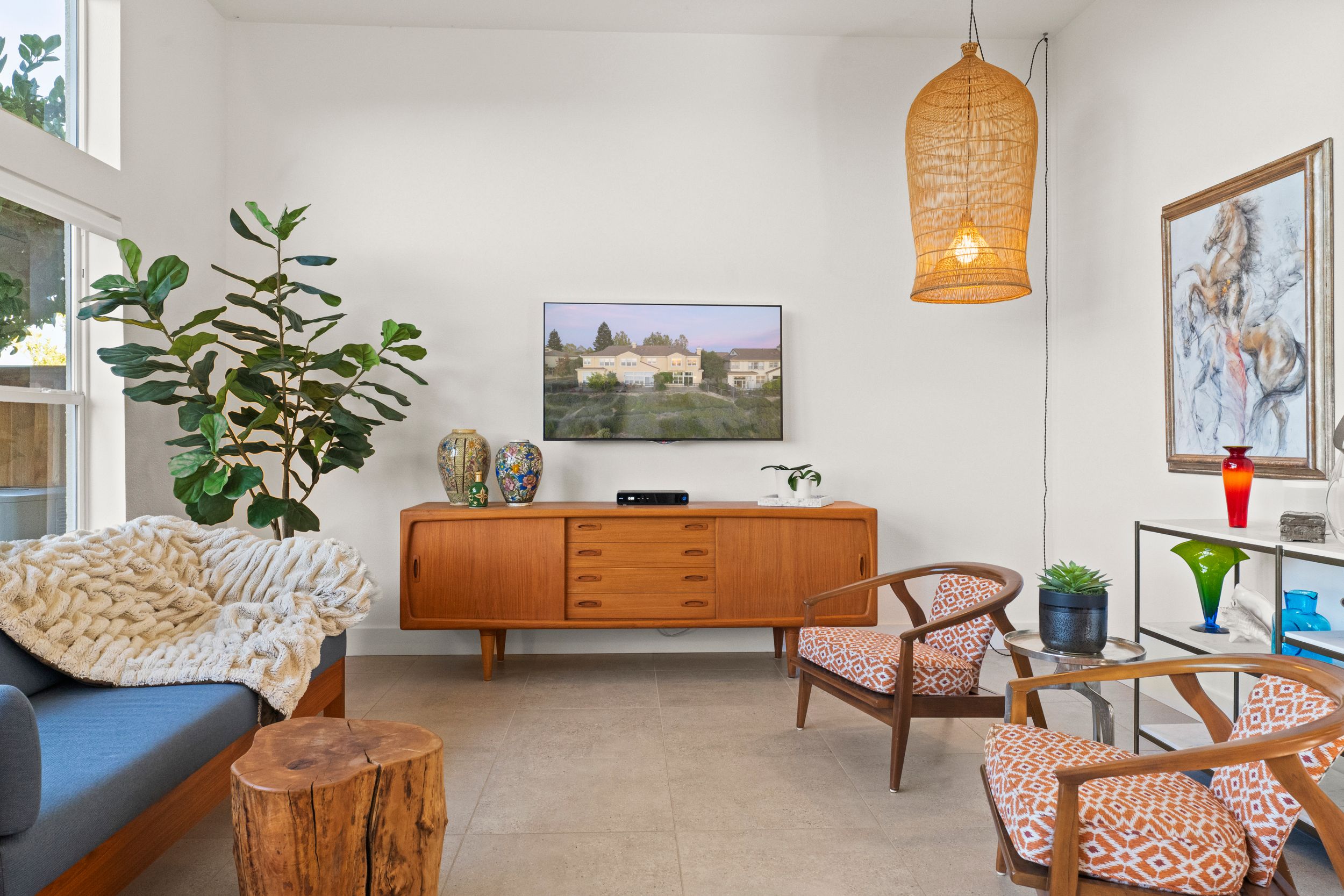 Bright living room with mid-century modern furniture, pendant light, and large windows bringing in natural light.