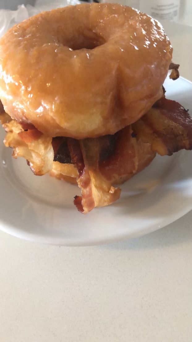 Glazed donuts with bacon filling arranged on white plates.
