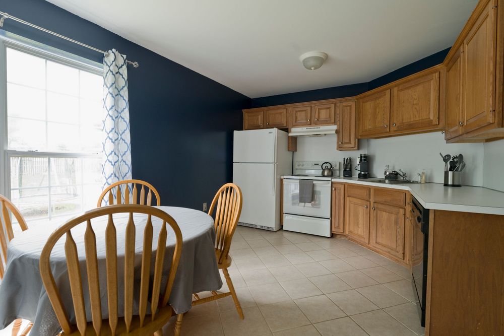 Kitchen interior with navy blue walls, oak cabinets, and a round dining table.