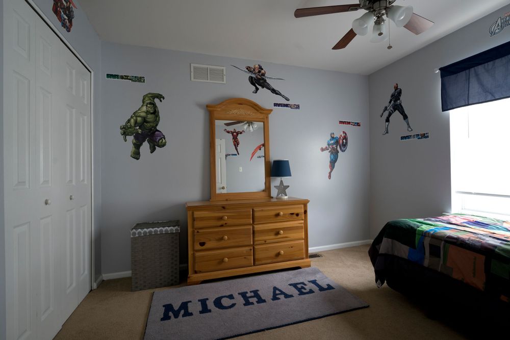 Children's bedroom with sports-themed wall decals, wooden dresser, and built-in closet storage.