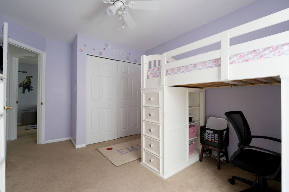 Purple-tinted bedroom with built-in loft bed, desk area, and white storage drawers.