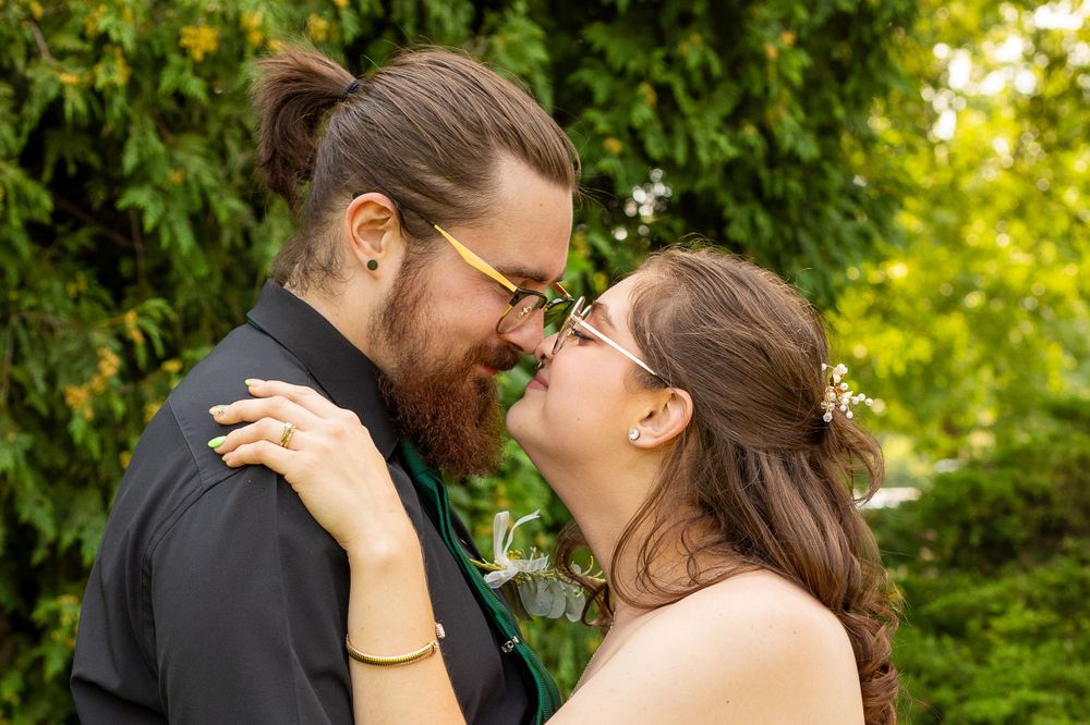 A couple shares a joyful moment during their wedding photoshoot in a garden setting.