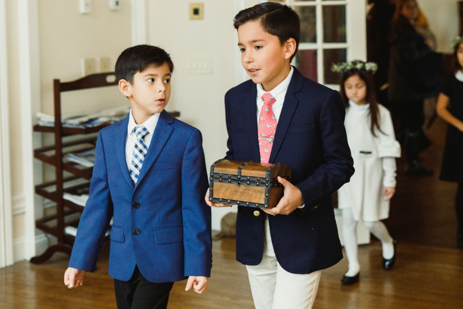 Young boys in formal attire stand together in a wood-paneled hallway during a wedding celebration.
