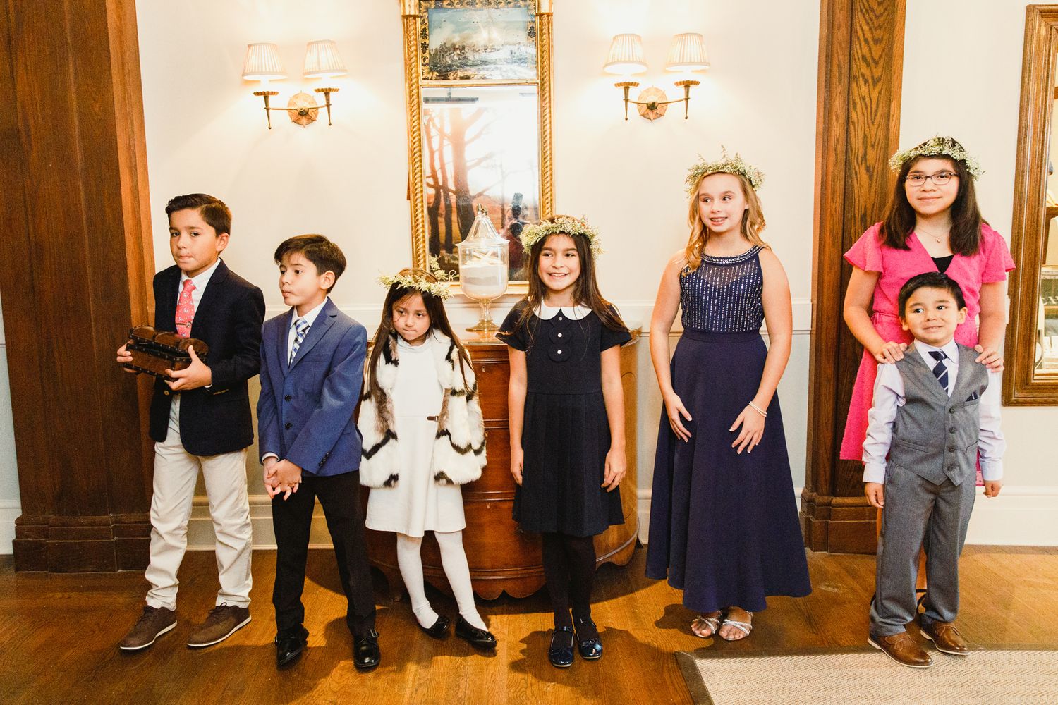 Children and adults lined up against a wall at a formal event.