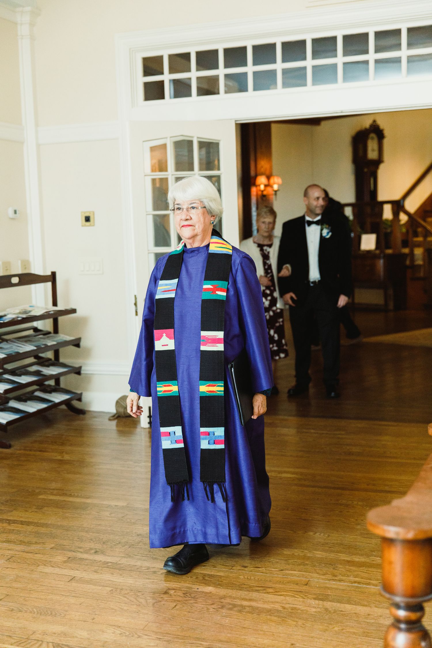 Display of ceremonial blue robes with colorful stoles on wooden hangers.