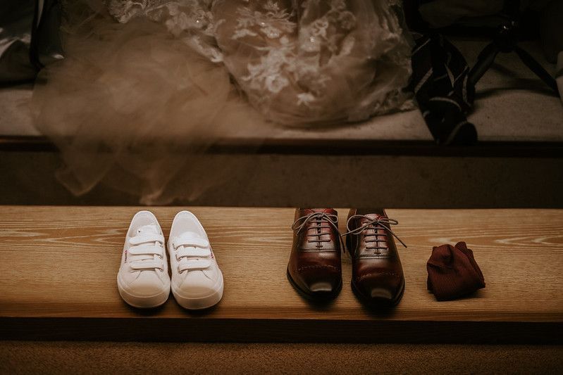 Wedding shoes arranged on a rustic wooden surface in warm lighting.