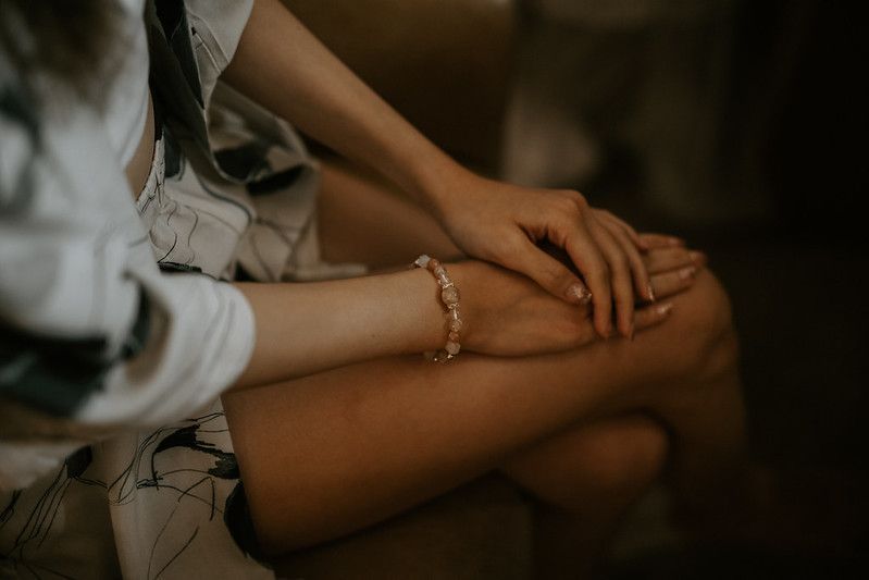 Close-up shot of hands resting on a surface in moody lighting.