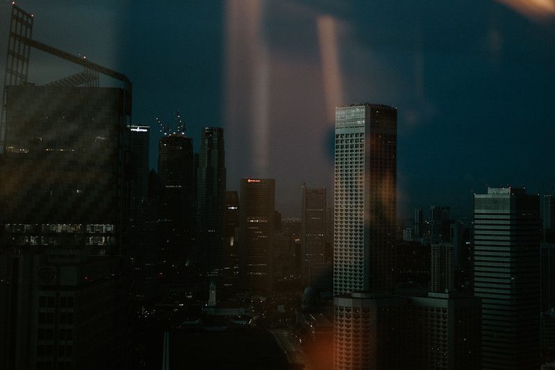 Dark moody cityscape with skyscrapers silhouetted against evening sky.