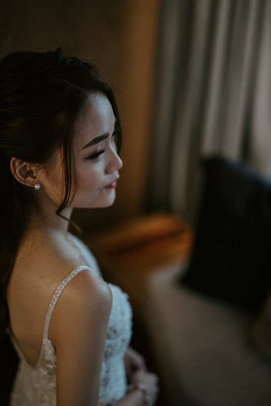 A bride in a lace wedding dress poses in moody lighting.