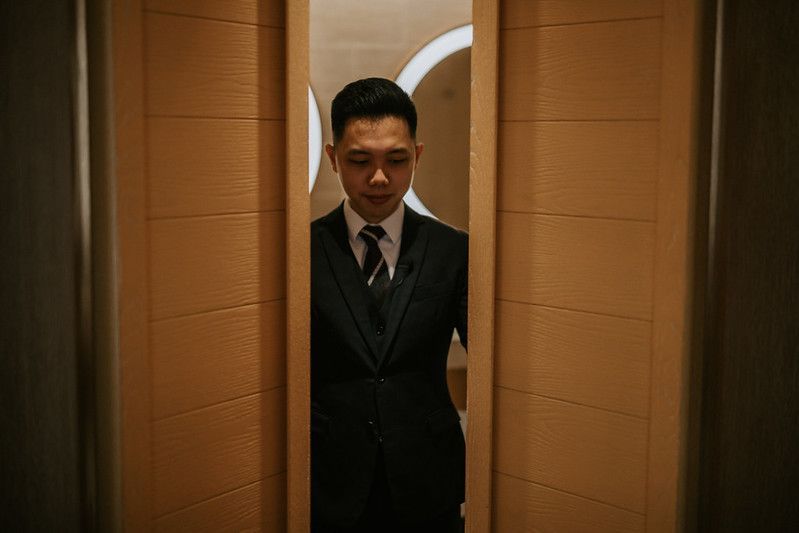 A groom in a dark suit stands in a doorway.