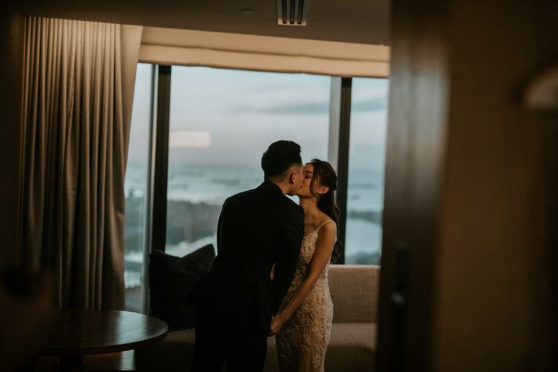 A couple shares a romantic moment while dancing in front of panoramic windows.