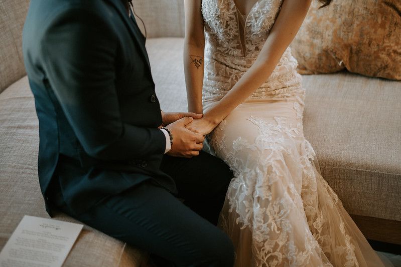 Couple sharing romantic moment on beige couch with sunlit windows.