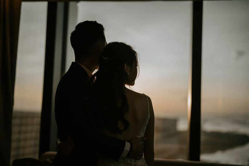 Dramatic silhouette of couple against window during golden hour.