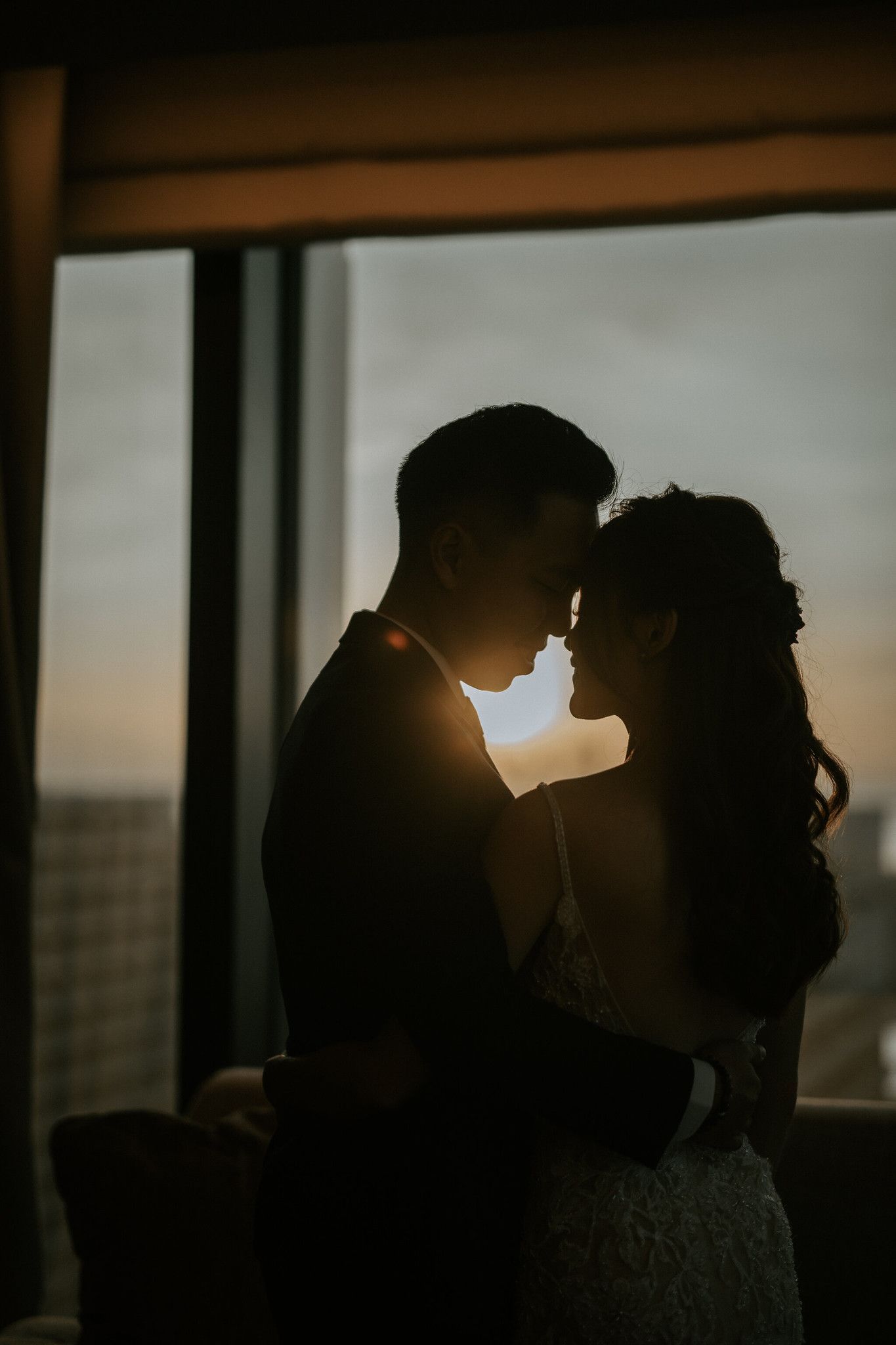 Silhouetted couple against sunset window creating romantic atmosphere.