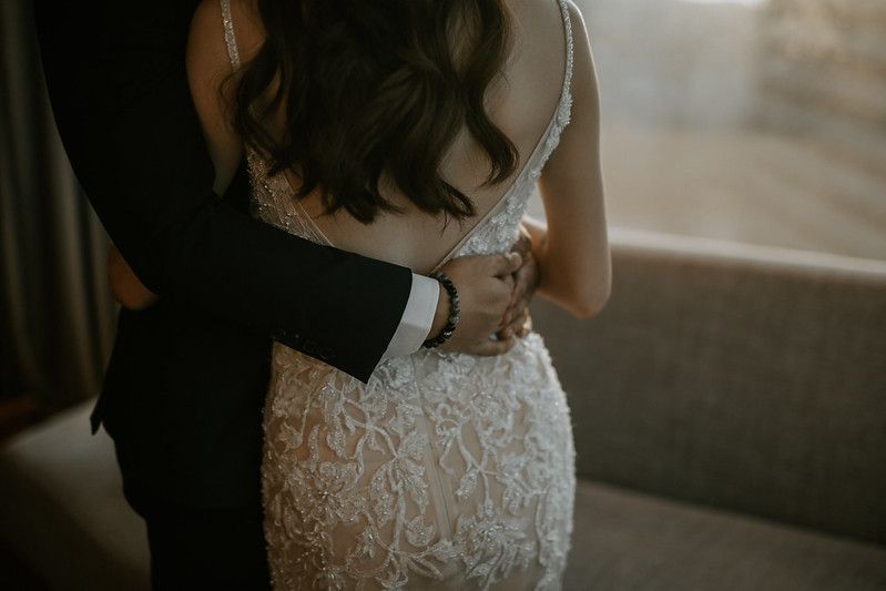 Back view of bride in detailed lace wedding dress being embraced.