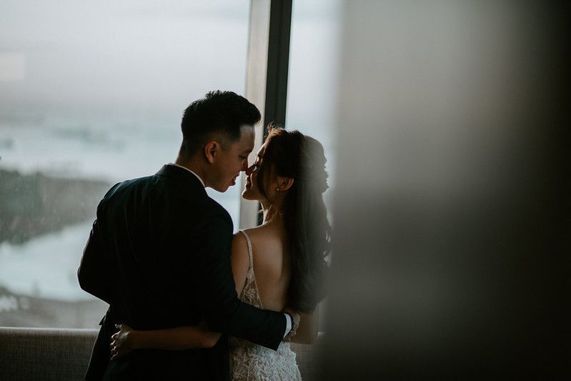 Silhouette of couple embracing by window during intimate wedding moment.