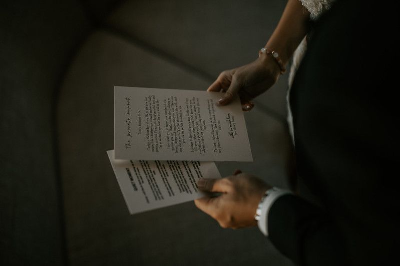 Hands holding wedding ceremony papers in dramatic lighting.