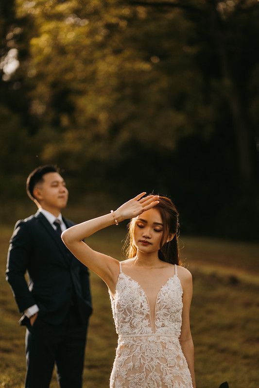 A couple poses in a romantic outdoor setting with golden sunlight filtering through autumn trees.