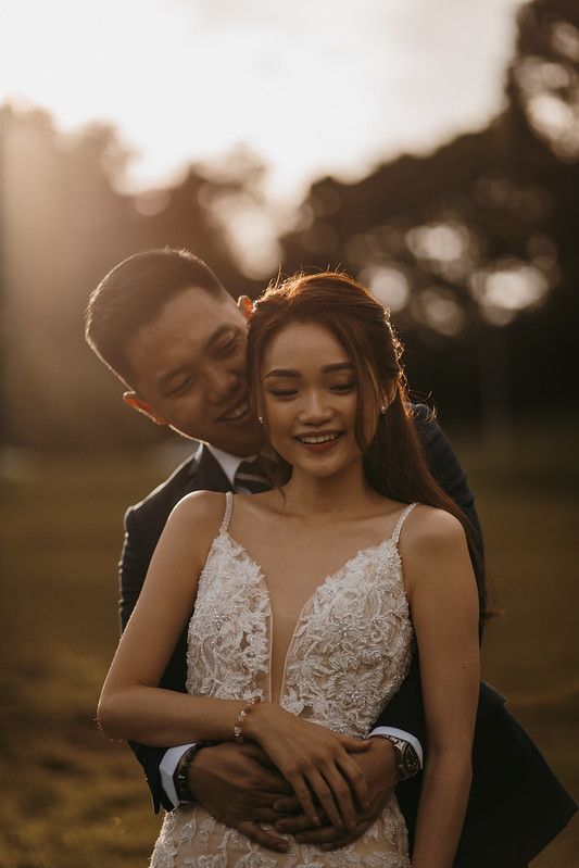 A tender embrace between newlyweds captured during golden hour in a natural outdoor setting.
