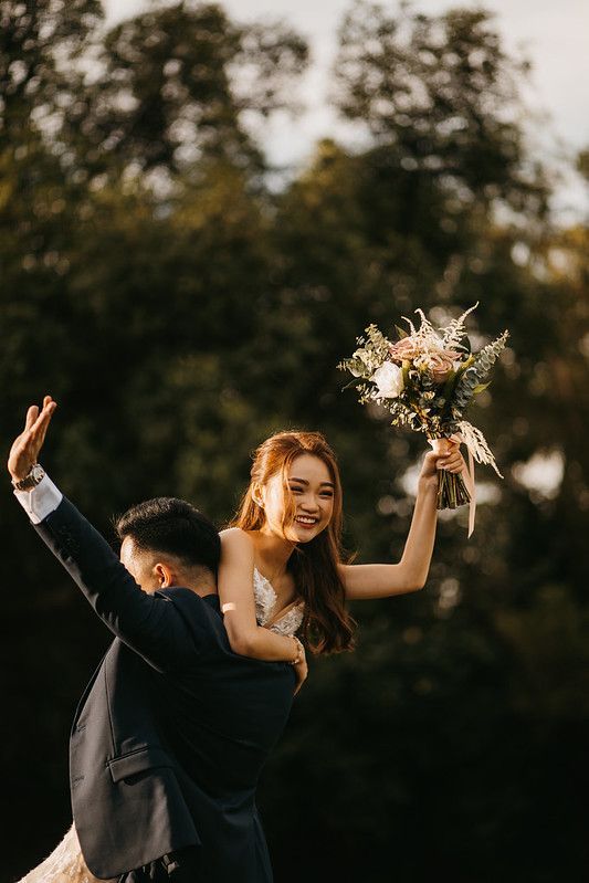 Joyful wedding couple dancing and celebrating outdoors during golden hour.
