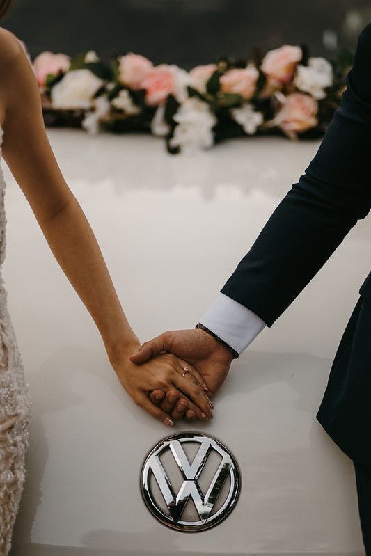 Close-up shots of hands touching the Volkswagen logo on a white car surface.