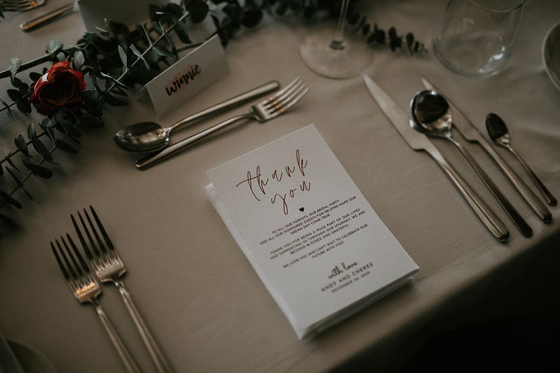 Elegant place settings with menu cards and silverware at a wedding reception.