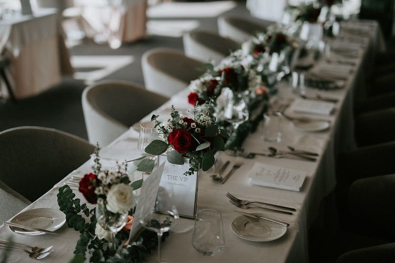 Wedding reception table decorated with white and burgundy floral centerpieces.