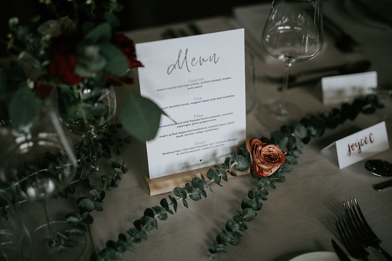 Elegant wedding table settings with white linens and greenery decorations in a modern dining space.