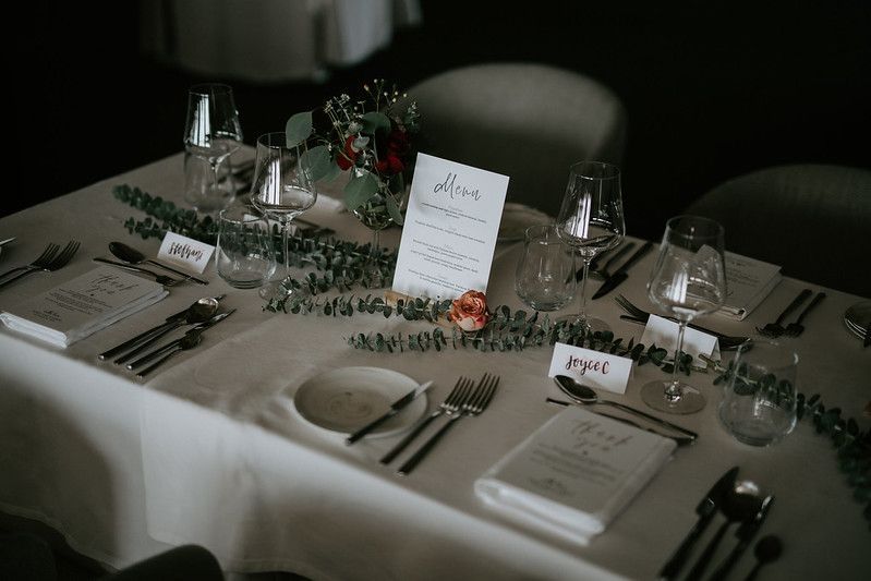 Minimalist table settings with menu cards and eucalyptus branches at a formal event.