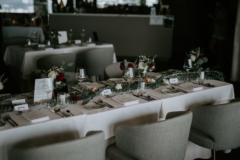 Wedding reception tables arranged with elegant place settings and natural decor in a modern venue.