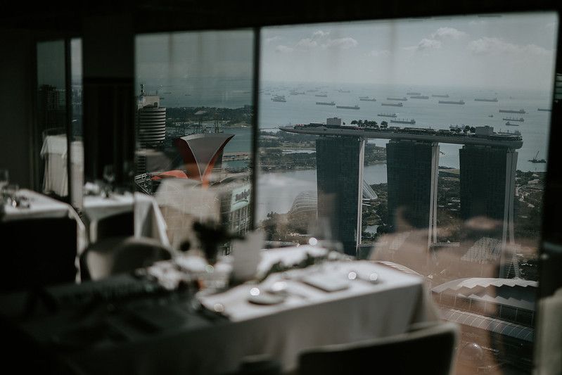 Panoramic view of an elegant dining setup with city skyline visible through large windows.