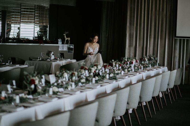 Long white dining tables arranged in rows with elegant place settings and floral decorations.