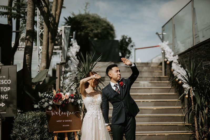 A romantic rooftop wedding ceremony setup with white drapes and floral arrangements against a city backdrop.