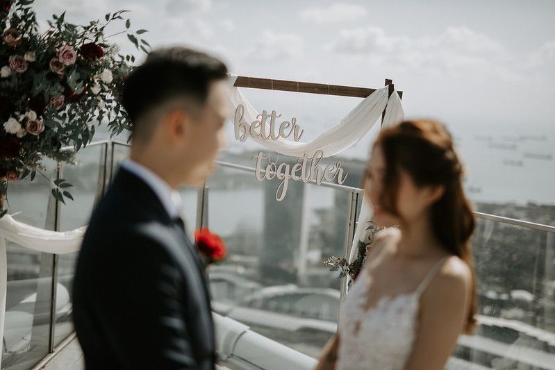 Romantic rooftop wedding moment under a fabric arch decorated with roses and greenery.