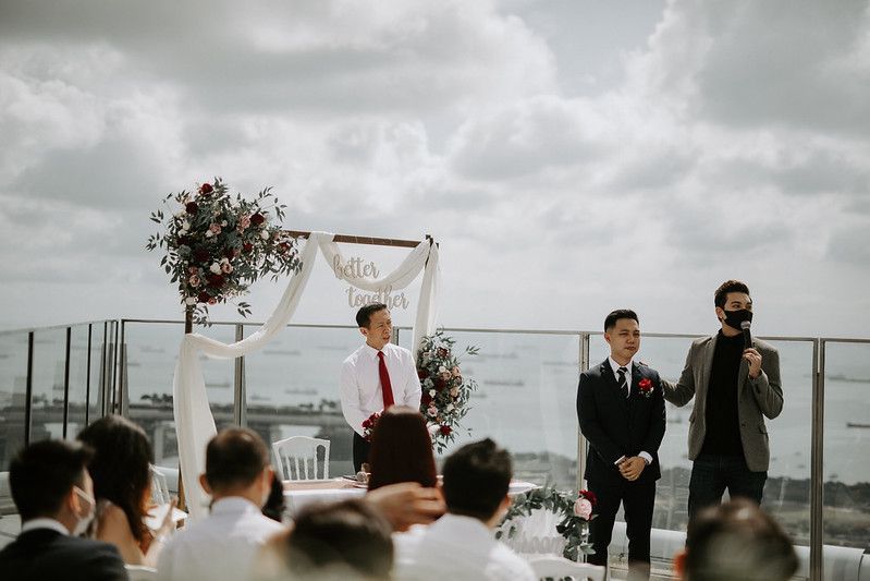 An elegant rooftop wedding ceremony with white decor and floral arrangements overlooking a city skyline.